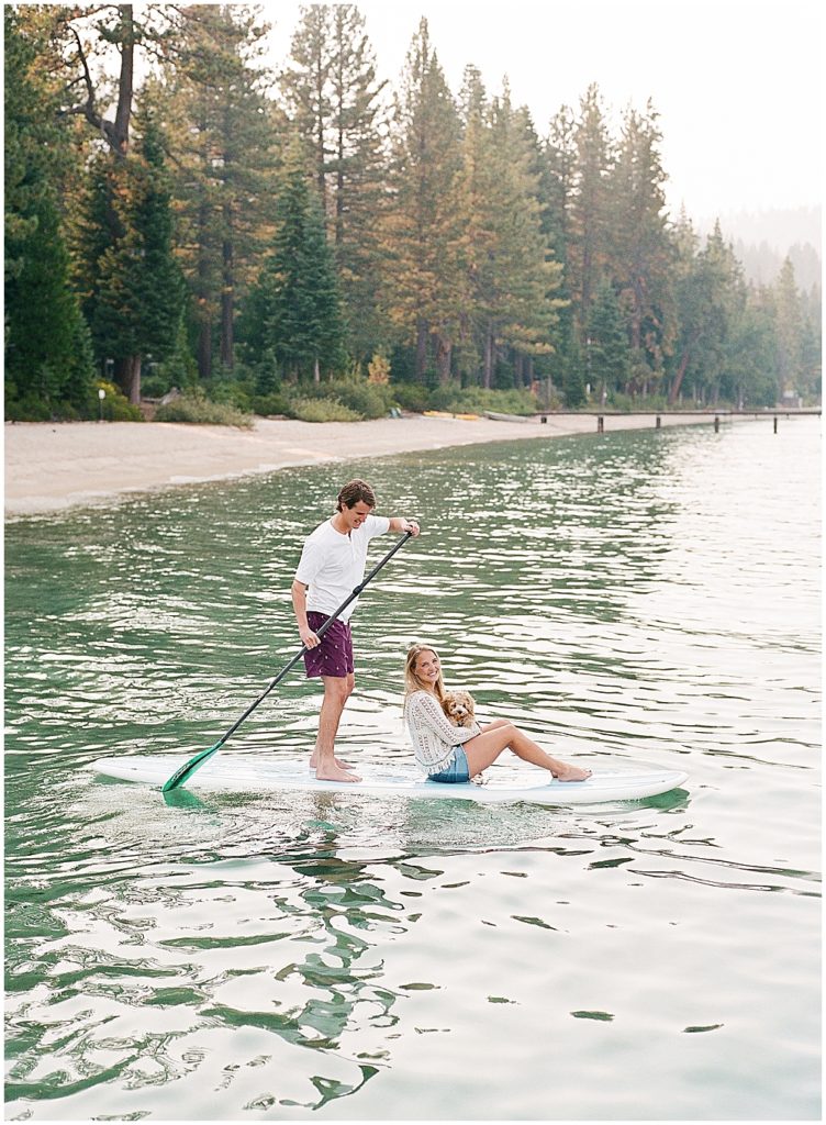 bride and groom paddle boarding with puppy